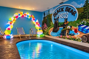 Ein Poolbereich mit Wandgemälde, Liegestühlen und einer farbenfrohen Ballonschleife.