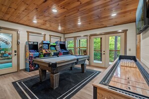 Une salle avec une table de billard, des jeux d’arcade et une table de jeu de palet.
