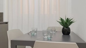 Ein Esstisch mit klaren Gläsern, einem Blumentopf und weißen Stühlen.