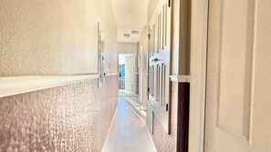 A hallway with a textured wall, a door with a handle, and a light fixture on the ceiling. - Family Retreat for 14 in Reunion Resort with Pool (Kissimmee)