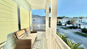 A porch with a wicker chair and a bench, overlooking a residential street with houses. - Family Retreat for 14 in Reunion Resort with Pool (Kissimmee)