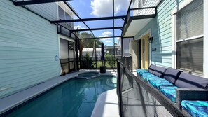 A swimming pool with a covered area, a seating area with cushions, and a view of the surrounding neighborhood. - Family Retreat for 14 in Reunion Resort with Pool (Kissimmee)