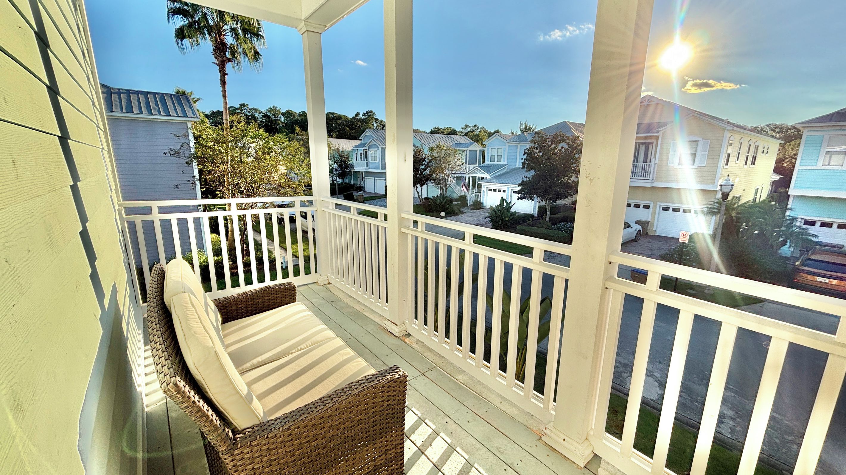 A covered porch with wicker furniture and a view of neighboring houses.