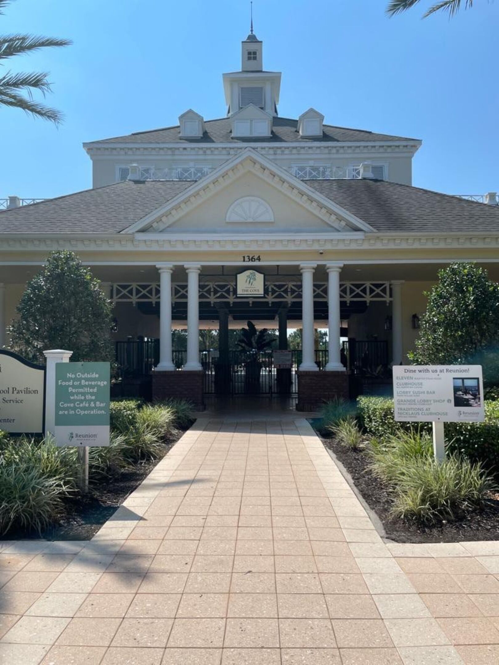 A building with a covered entrance, columns, and a sign indicating 'The Cove' with a number '1364'.