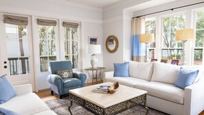 Una sala de estar con un sofá blanco, un sillón azul y una mesita de centro.