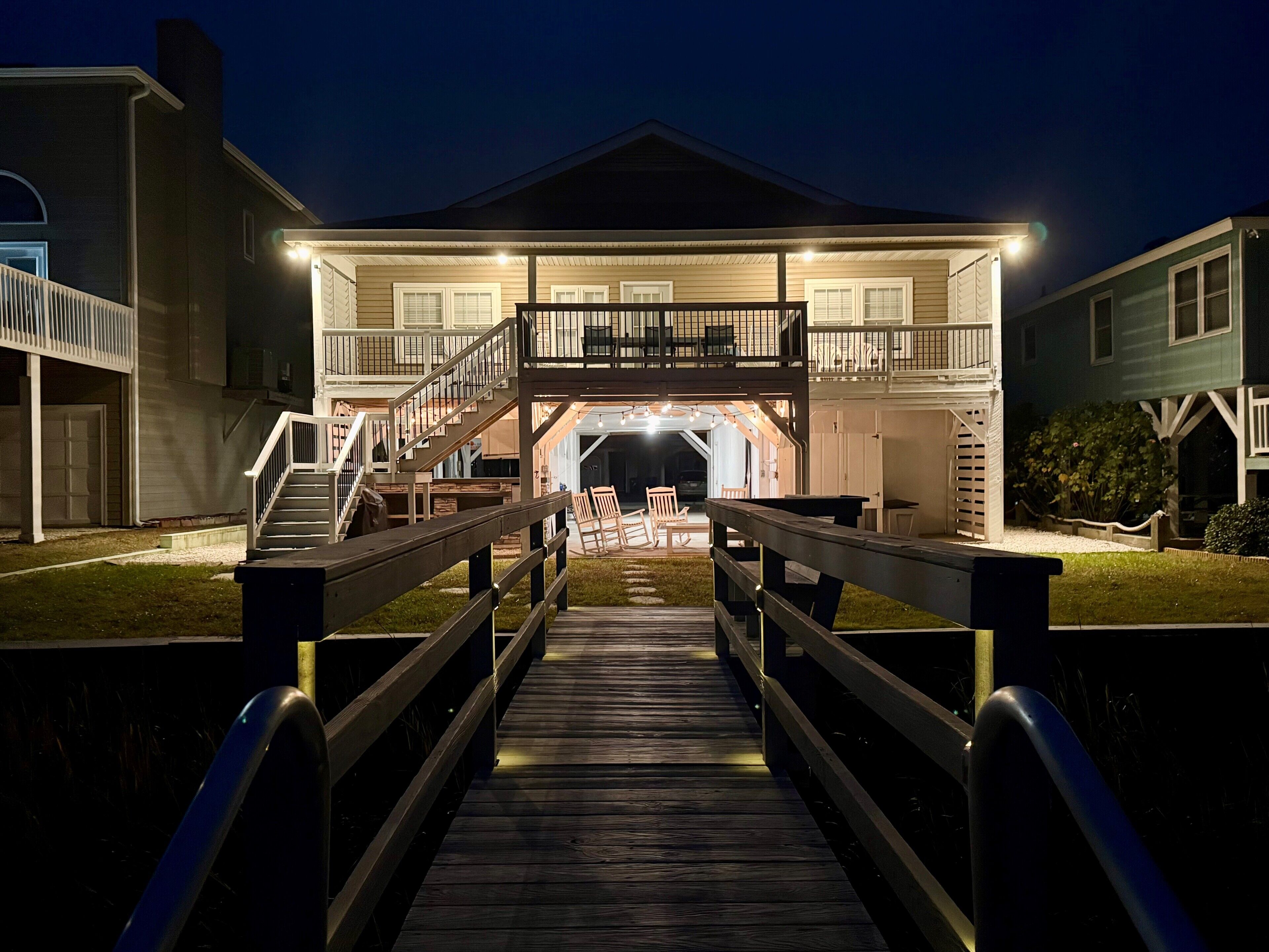 A two-story building with a covered entrance, a wooden deck leading to the entrance, and a staircase.