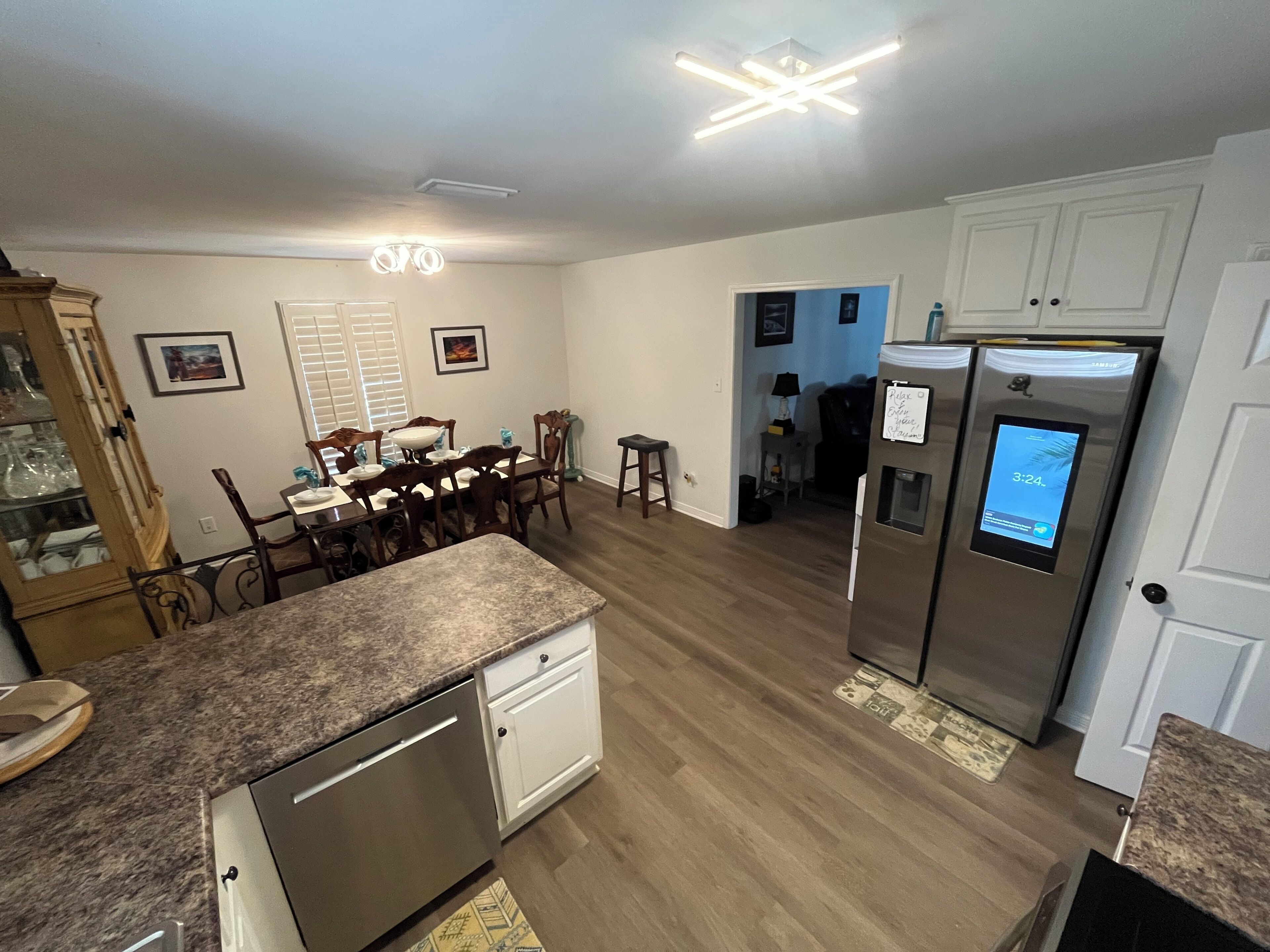 A modern kitchen with granite countertops, stainless steel appliances, and a dining area with wooden chairs and a table.