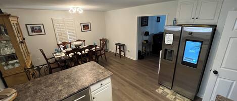 A modern kitchen with granite countertops, stainless steel appliances, and a dining area with wooden chairs and a table.