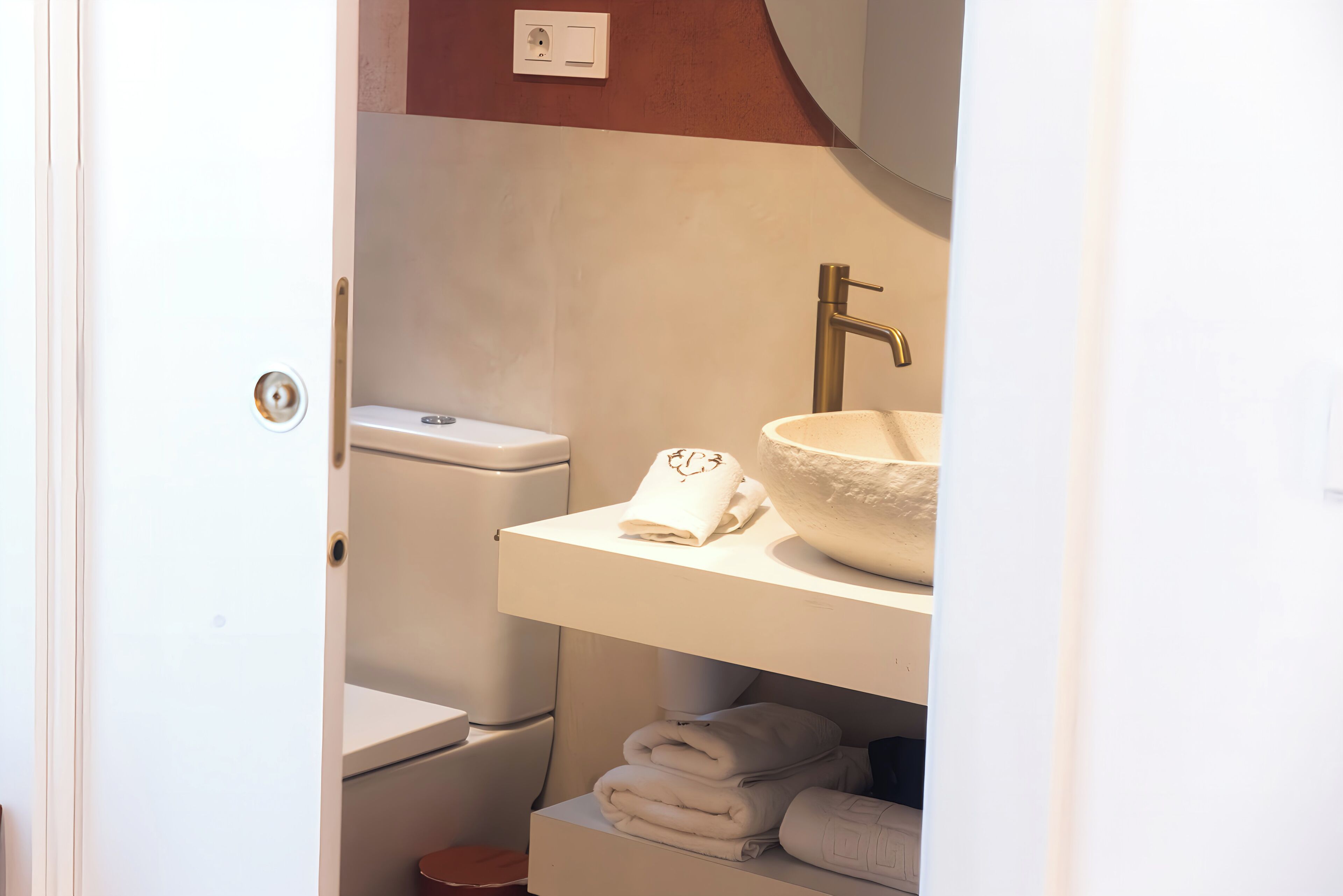 Une salle de bain équipée de toilettes, d’un lavabo et d’un espace pour ranger les serviettes.