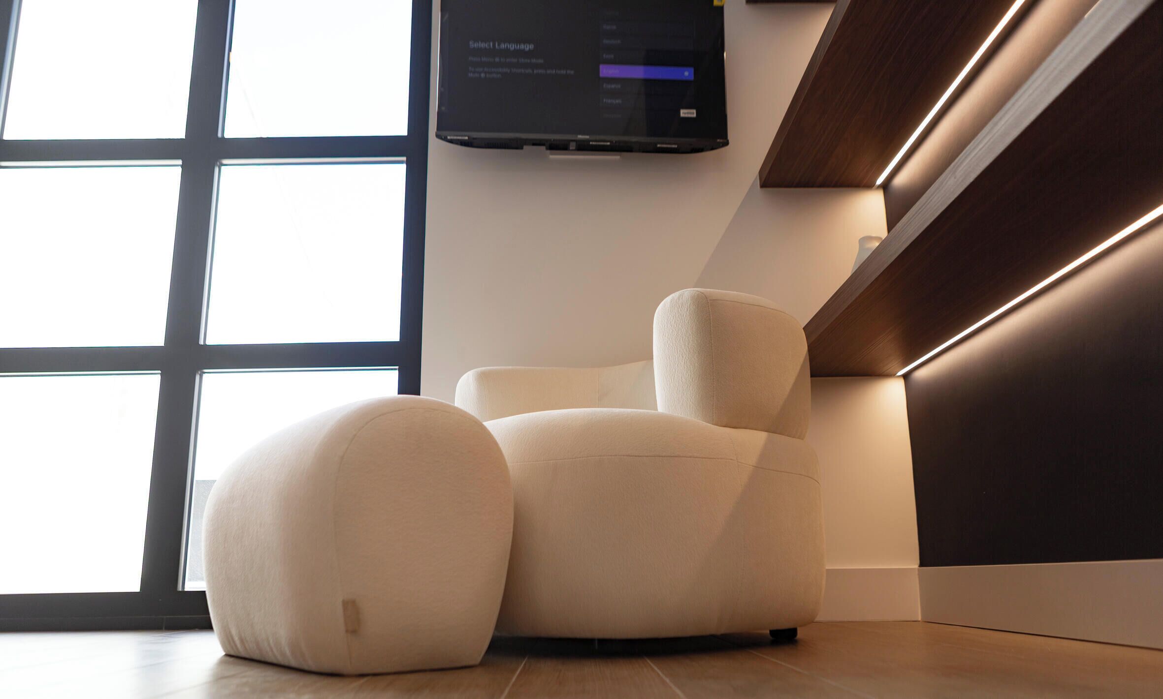 A modern chair with a cushioned seat and backrest, positioned near a window with a view of the outside.