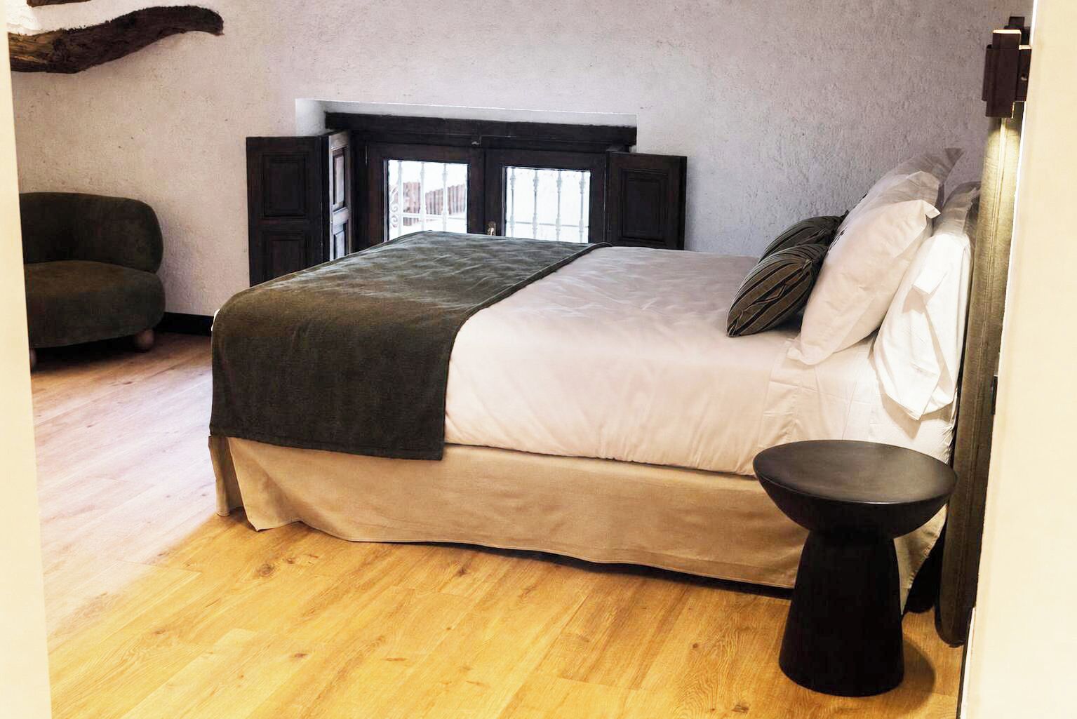 A bedroom with a bed, a bedside table, a chair, and a window.