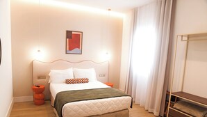 A modern hotel room with a bed, bedside tables, a nightstand, a mirror, and a window with curtains. - Platea Concept Suites (Caudete)