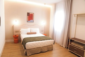 A modern hotel room with a bed, bedside tables, a nightstand, a mirror, and a window with curtains.