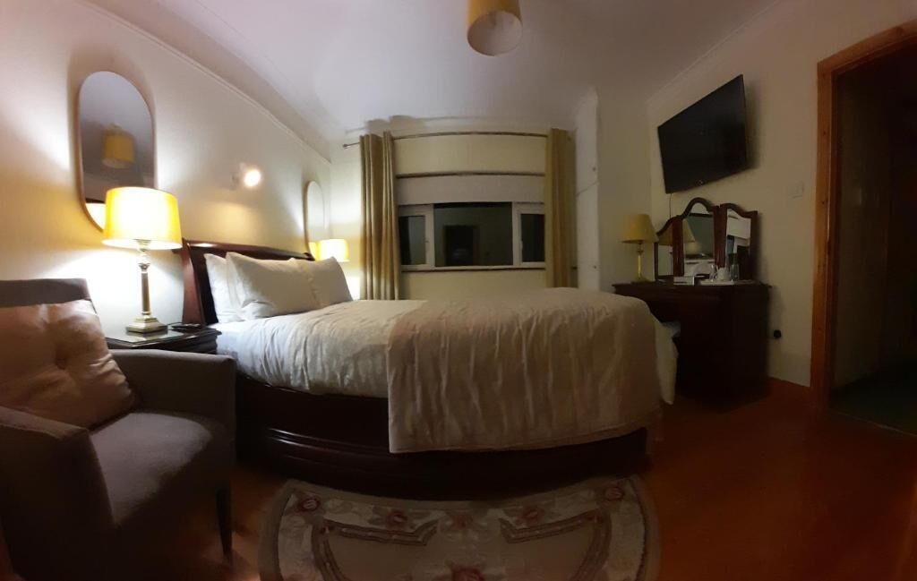 Habitación de hotel con cama, una silla, un escritorio, televisión y ventana.