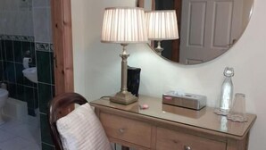 A wooden desk with a chair, a lamp, a mirror, and a small table with a tissue box and a glass. - Woodhaven Manor  (Galway)