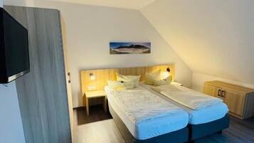 A bedroom with a bed, bedside tables, a TV, and a ceiling light.