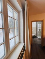 Un pasillo estrecho con una ventana a la izquierda y una puerta que da a un baño a la derecha.