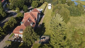 An aerial view of a property with multiple buildings, a parking area, and a body of water.