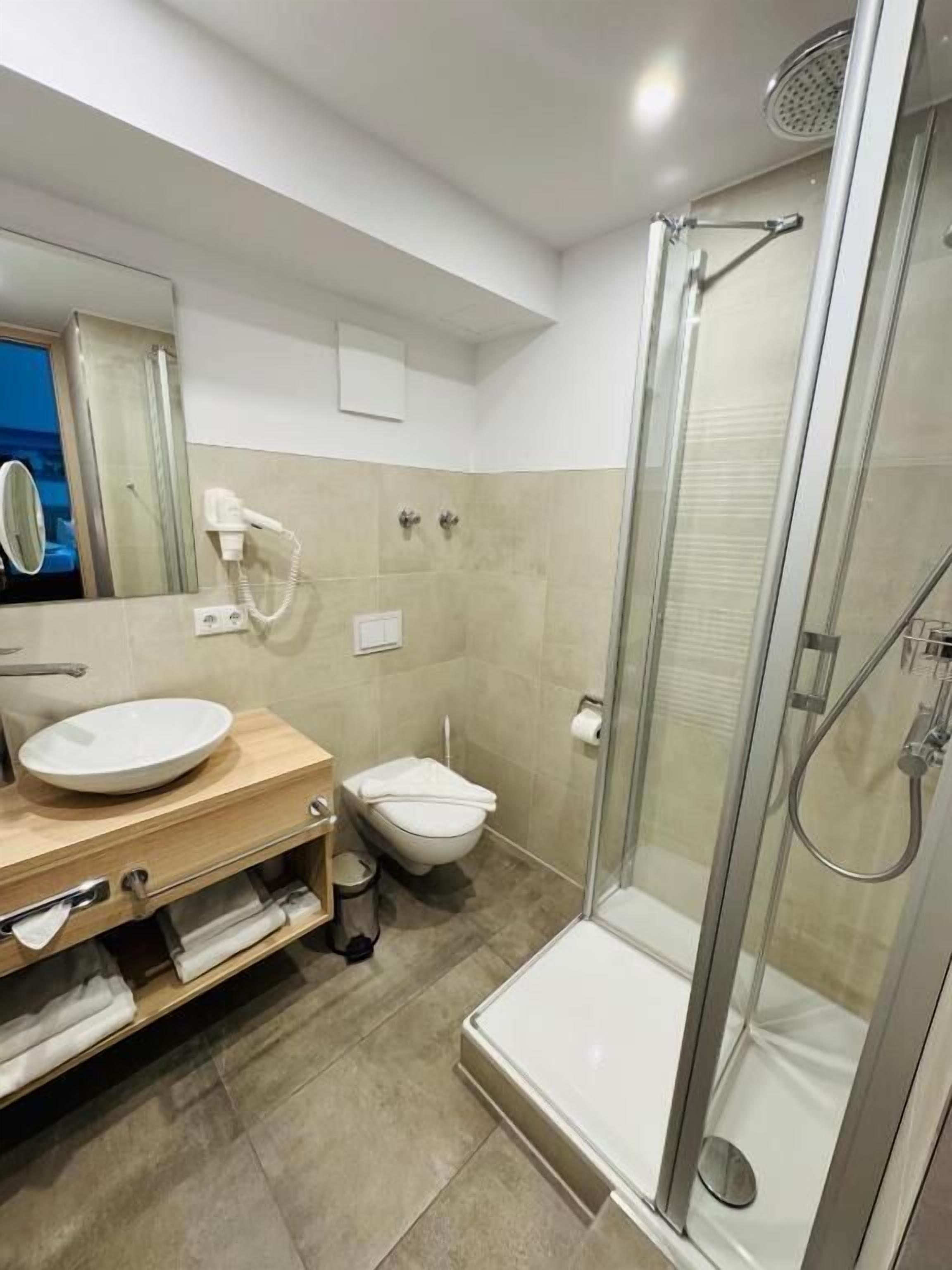 A modern bathroom with a glass-enclosed shower, a sink with a mirror, and a toilet.
