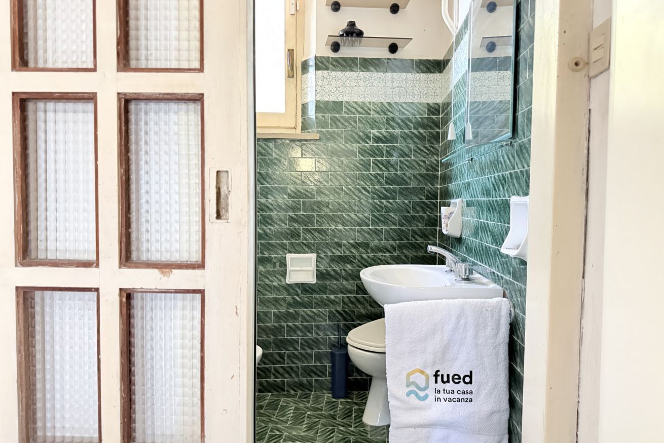 A bathroom with a toilet, sink, and a towel hanging on the wall.