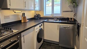 Una cocina funcional con estufa a gas, lavadora y lavavajillas.