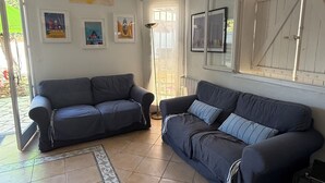 Un salon avec deux canapés de couleur foncée, un tapis à motifs, un ventilateur de plafond et une grande fenêtre donnant sur un beau paysage.