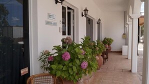 A hotel entrance with a sign, potted plants, and a tiled floor. - La Posada de los Robles (Las Grutas)