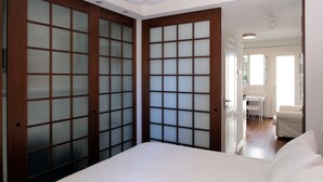 A bedroom with a bed, a wooden wardrobe with frosted glass panels, a white ceiling light, and a door leading to a bathroom. - Casa Gelsomino | Private terrace, 15-minute walk to Piazza Maggiore ⭐ (Bologna)