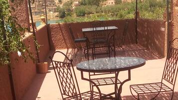 Une terrasse extérieure avec une table et des chaises, un tapis à motifs et une vue sur un paysage vallonné.