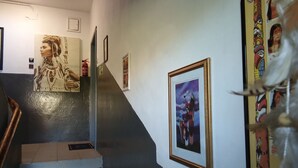 Een trap met een leuning, een brandblusser en kunstwerken in lijsten aan de wanden.