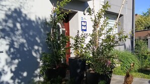 Een modern gebouw met een verzorgde tuin, met verschillende planten en een vogelbeeldhouwwerk.
