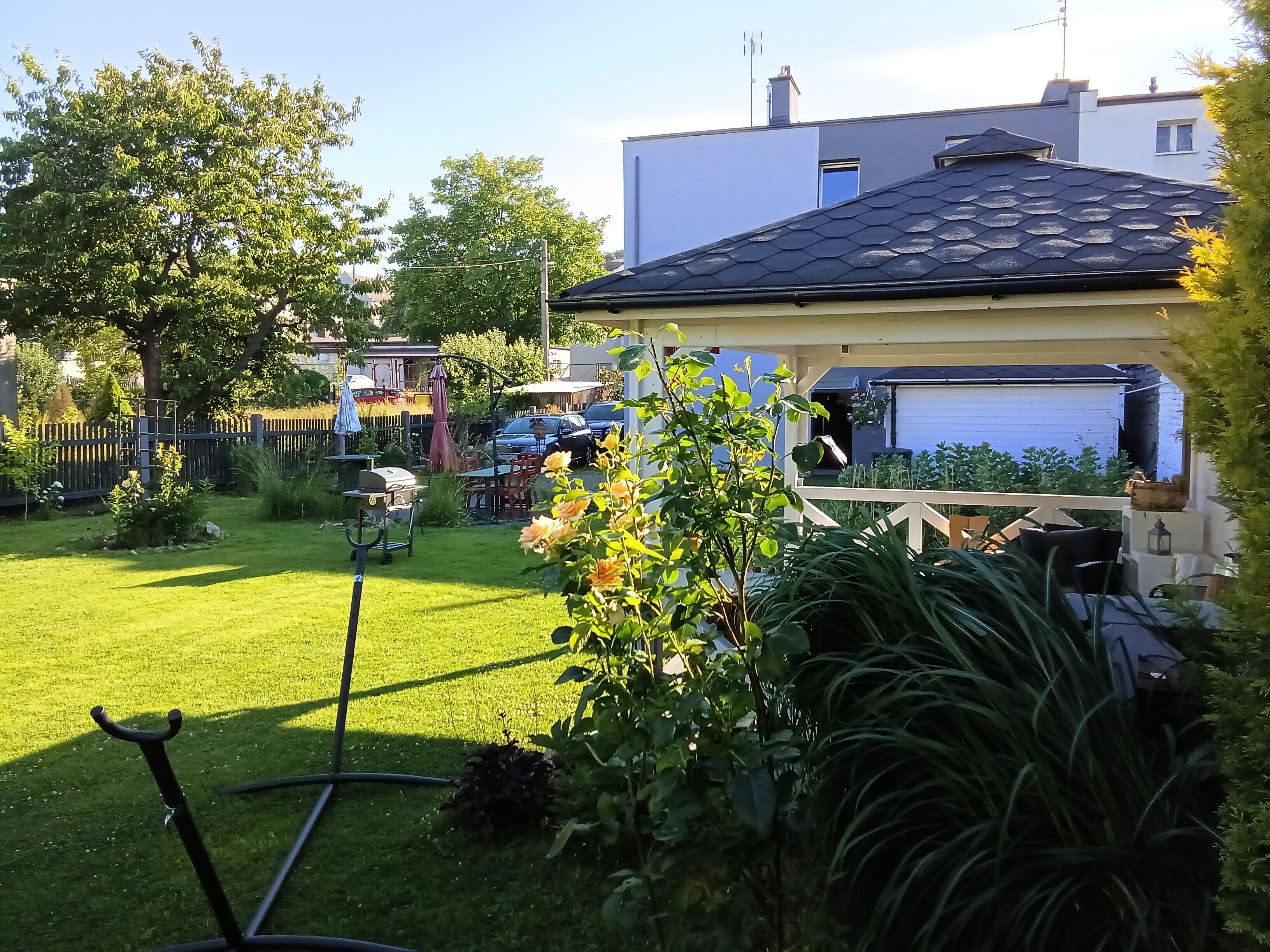 Een achtertuin met gazon, barbecue, houten schutting en garage.