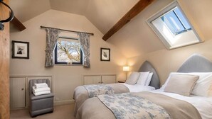 A bedroom with two beds, a window with curtains, a bedside lamp, and a small table with a chair. - Fox Cottage / Luxury 2 Bed (sleeps 4) with stunning views and 4 acre dog field (Matlock)