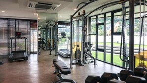 A gym with exercise equipment, a bench, and large windows. - 6th Avenue Surin by Win217 (Choeng Thale)