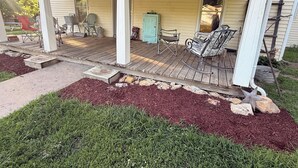 Eine überdachte Veranda mit Gartenmöbeln, einem Briefkasten und einer Holzterrasse.