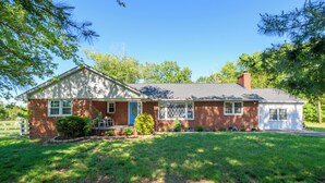 A single-story brick house with a front porch, a small front yard, and a garage.