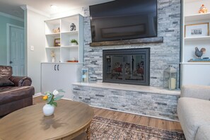 Un salon doté d’une cheminée en pierre, d’un téléviseur à écran plat fixé au-dessus et d’un canapé en cuir marron.