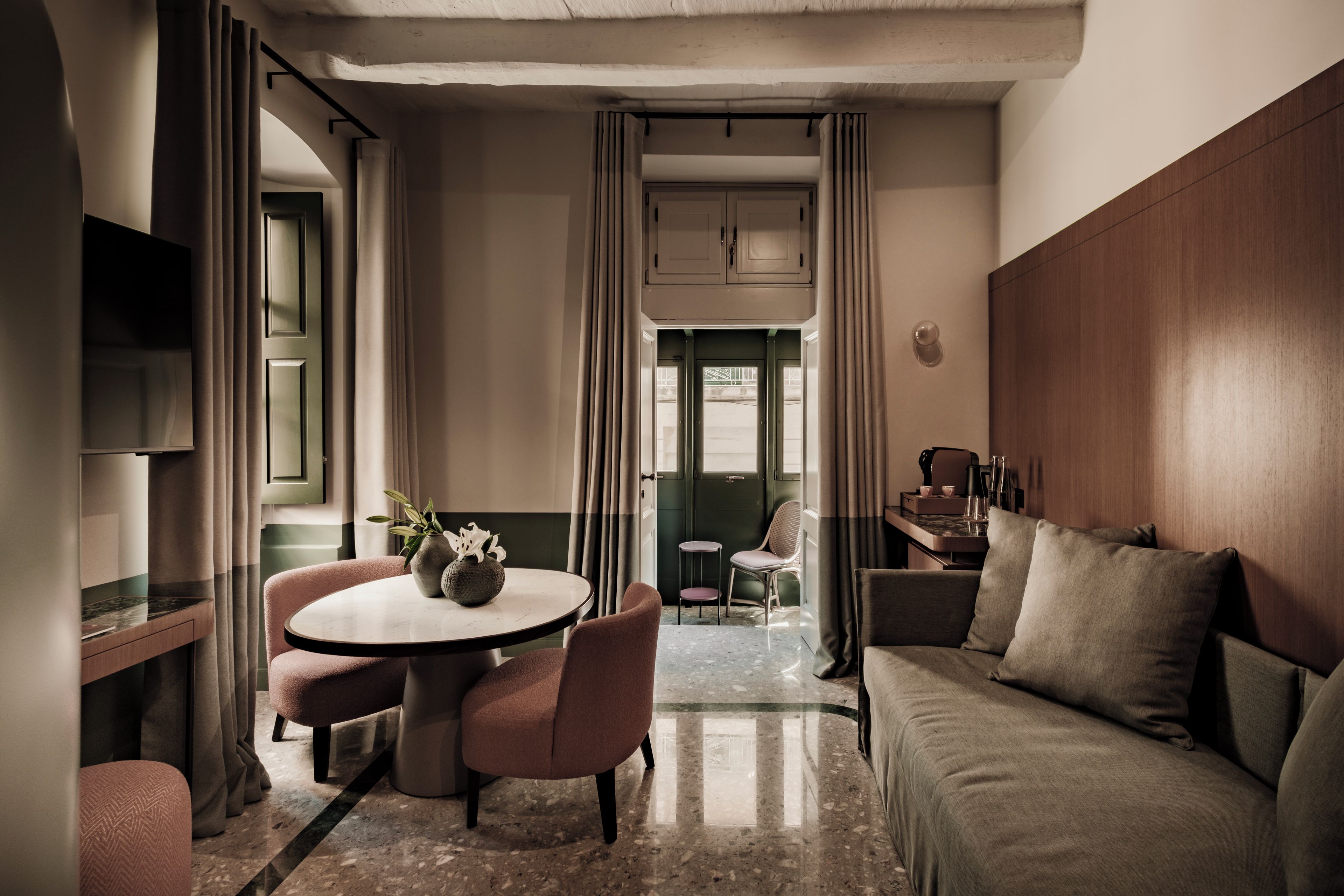Habitación de hotel con una mesa redonda, dos sillas, un sofá, un televisor y vistas al exterior.