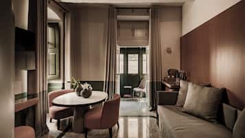 Habitación de hotel con una mesa redonda, dos sillas, un sofá, un televisor y vistas al exterior.