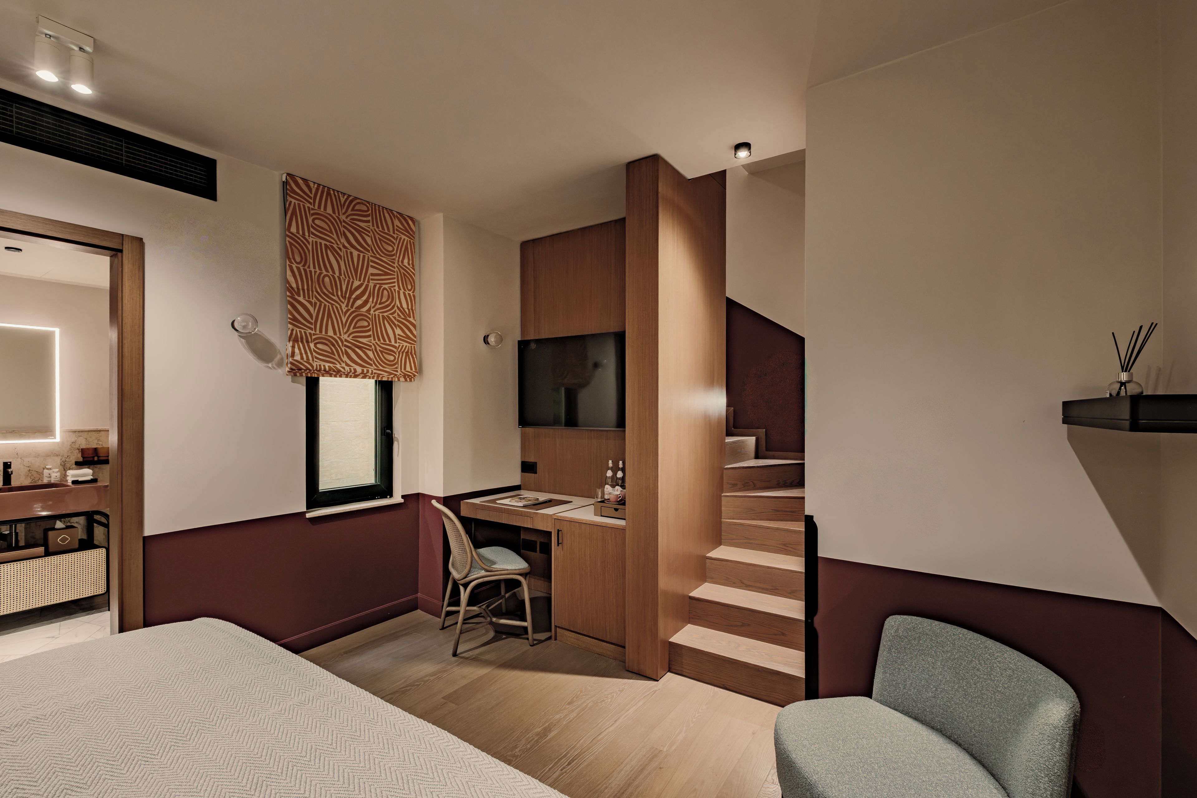 Een moderne hotelkamer met een bed, bureau, stoel en een trap.