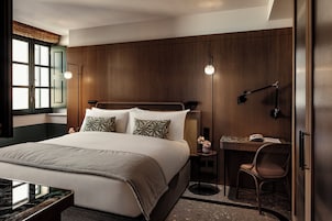 Ein modernes Hotelzimmer mit einem großen Bett, einem Schreibtisch und einem Sessel.