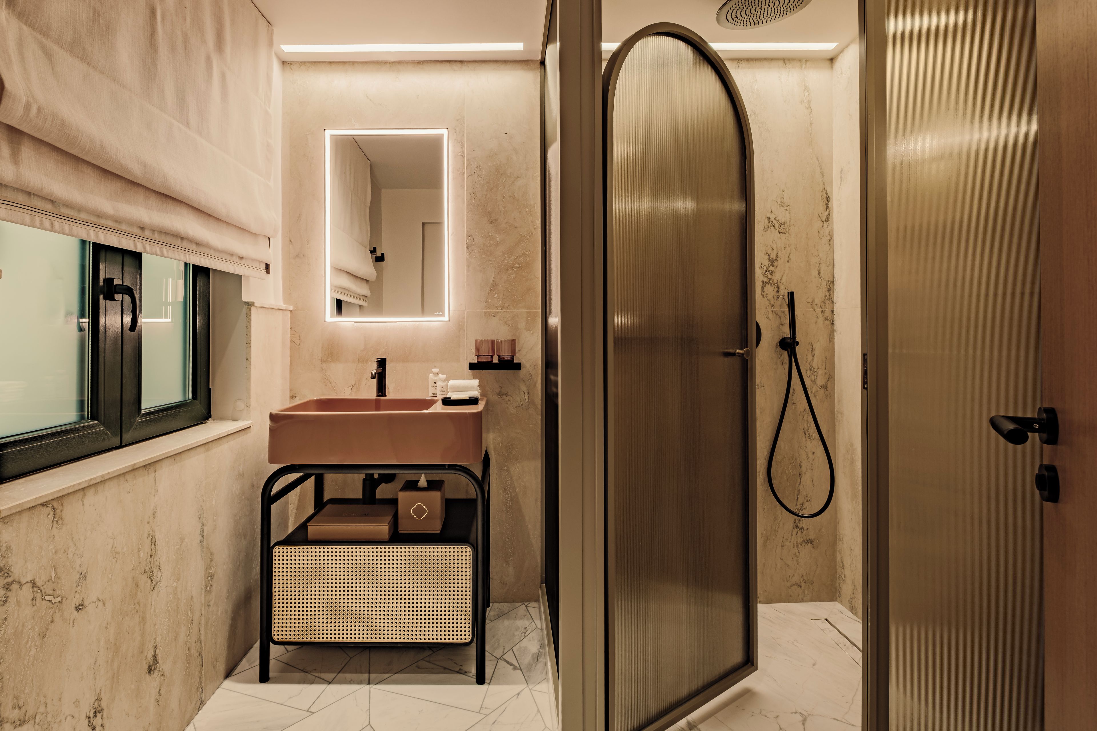 Un baño moderno con cabina de ducha de vidrio, lavabo con tocador y espejo con iluminación integrada.