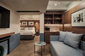Una habitación de hotel moderna con una cama, un sofá, una mesita y un televisor.