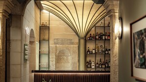Un espace bar doté d’un sol carrelé, d’un comptoir et d’un coin salon avec une table et des chaises.