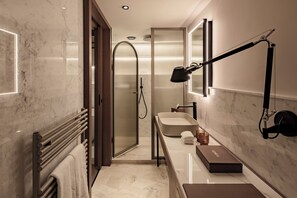 Un baño moderno con piso de mármol, cabina de ducha, tocador con espejo y perchero.