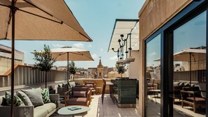 Une terrasse sur le toit, avec des sièges en plein air, des parasols et une vue sur le paysage urbain.