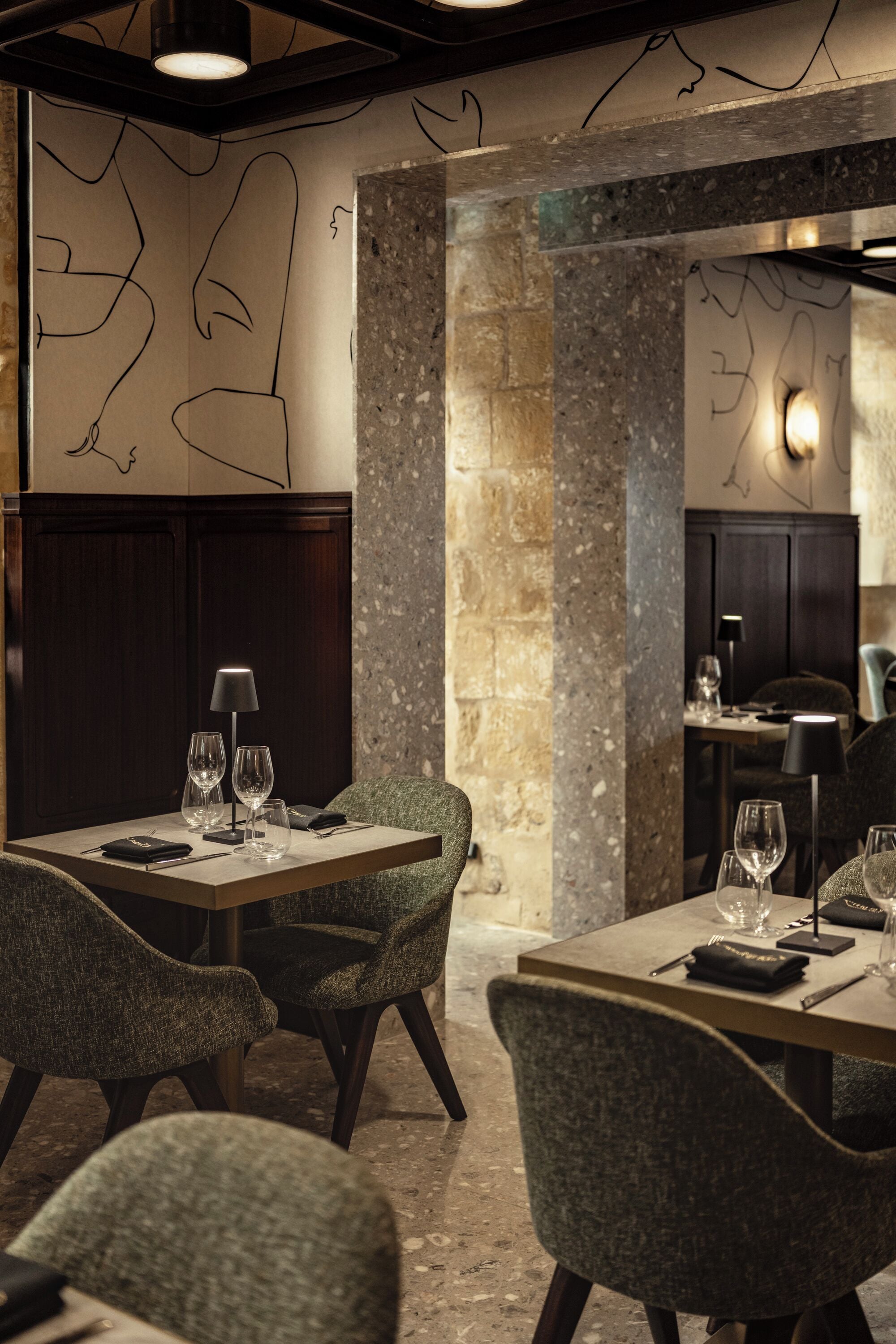 A restaurant with a stone wall, wooden paneling, and a table set with glasses and cutlery.