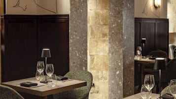 A restaurant with a stone wall, wooden paneling, and a table set with glasses and cutlery.