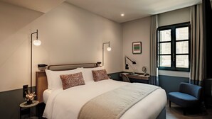 Une chambre d’hôtel avec un grand lit, des tables de chevet, un bureau et une chaise.