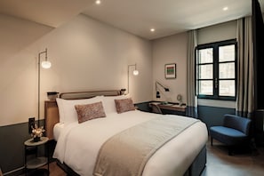 A hotel room with a large bed, bedside tables, a desk, and a chair. - Romègas Hotel (Valletta)